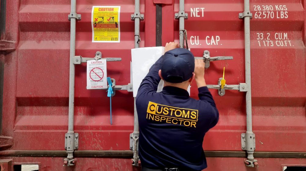 Customs inspector sealing a red shipping container